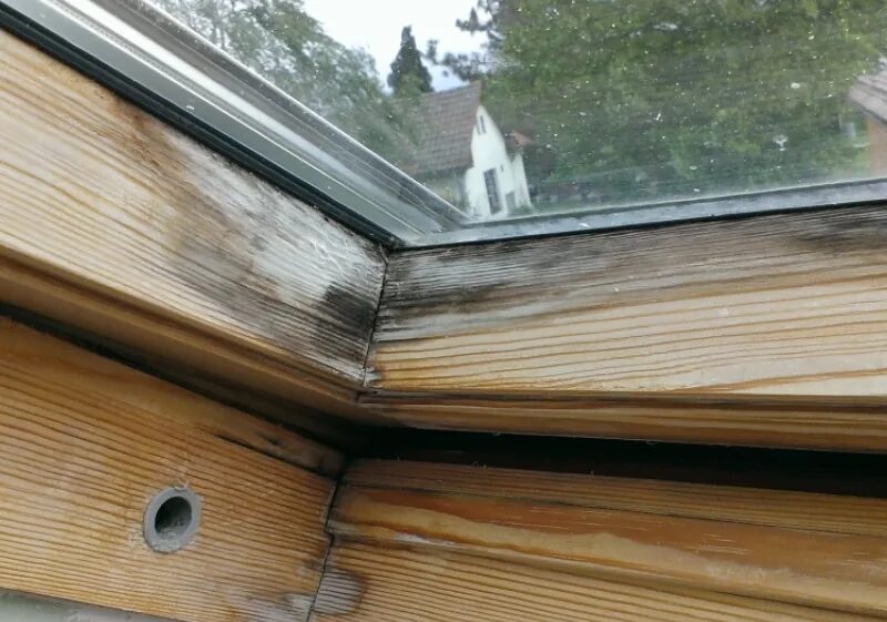 Střešní okno Velux s poškozeným lakem a zašedlým dřevem rámu